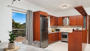 A modern kitchen with wooden cabinets, stainless steel appliances, and a dining area with a table and chairs. - The cozy nook (Chorafakia)