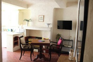 Cozy living and dining space with a dining table, chairs, TV, and kitchenette.
