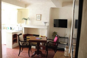 Cozy living and dining space with a dining table, chairs, TV, and kitchenette.