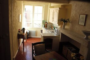 Compact kitchen with sink, stove, and countertop, featuring a tiled backsplash and cabinet.