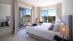 Ein modernes Hotelzimmer mit einem großen Bett, einem Balkon mit Glastür und Blick ins Freie.