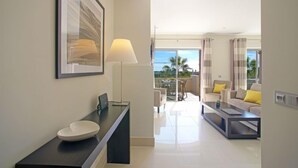 Ein modernes Hotelzimmer mit großem Fenster, einem Balkon, einem Essbereich und einem Badezimmer mit großem Waschbecken und einem gerahmten Bild.