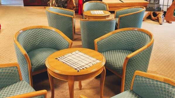 A room with six green upholstered chairs and a wooden table with a placemat.