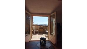 Una habitación con puerta corrediza de vidrio que da a un patio exterior con mesa y sillas.