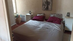 Un dormitorio con una cama grande, una mesita de noche y un radiador, además de una ventana.