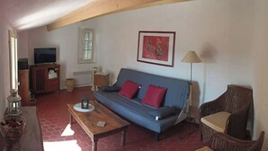 Una sala de estar acogedora con un sofá, una mesa de centro, un televisor y una lámpara.