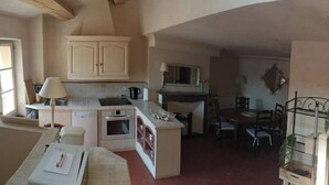 Una cocina compacta con comedor, una escalera y un ventanal.