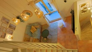 Eine Treppe mit Blick auf einen Raum, der ein Bett, einen runden Tisch und ein Fenster zeigt.