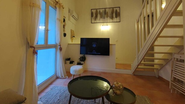 Ein Wohnzimmer mit Fernseher, Treppe und einem Fenster mit Vorhängen.