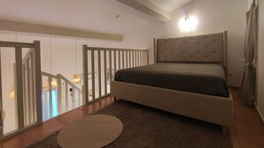Ein Schlafzimmer mit einem großen Bett, einer Holztreppe und Blick ins Freie.