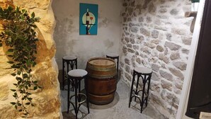 Ein rustikaler Keller mit Steinwänden, Holzfässern und zwei Hockstühlen.