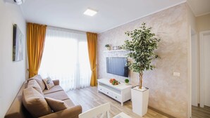 A modern living room with a sofa, TV stand, and a potted plant. - Cappuccino Colors at West Residence (Oradea)