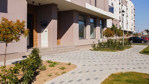 A modern building with a flat roof, large windows, and a paved walkway. - Cappuccino Colors at West Residence (Oradea)