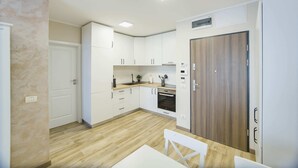 A modern kitchen with white cabinets, a wooden door, and a built-in oven. - Cappuccino Colors at West Residence (Oradea)