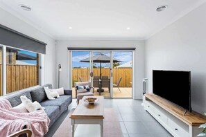 Una sala moderna con sofá, mesa de centro y televisor de pantalla plana.