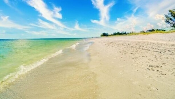 Een strand met helder water en een zandkust.
