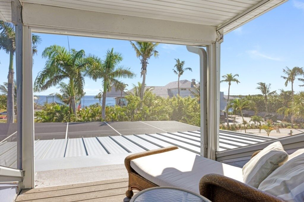 Quarto com vista para palmeiras e praia.