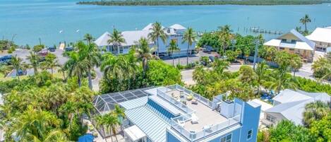A coastal property with a large building, palm trees, and a view of the sea.