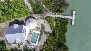 Eine Vogelperspektive eines Küsteneigentums mit Schwimmbad, einem großen weißen Gebäude und einer anlegenden Mole.