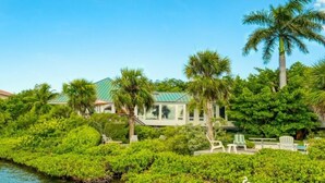 A coastal property with a house, palm trees, and a water body. - Little Current 3 Bedroom Home by RedAwning (Captiva)