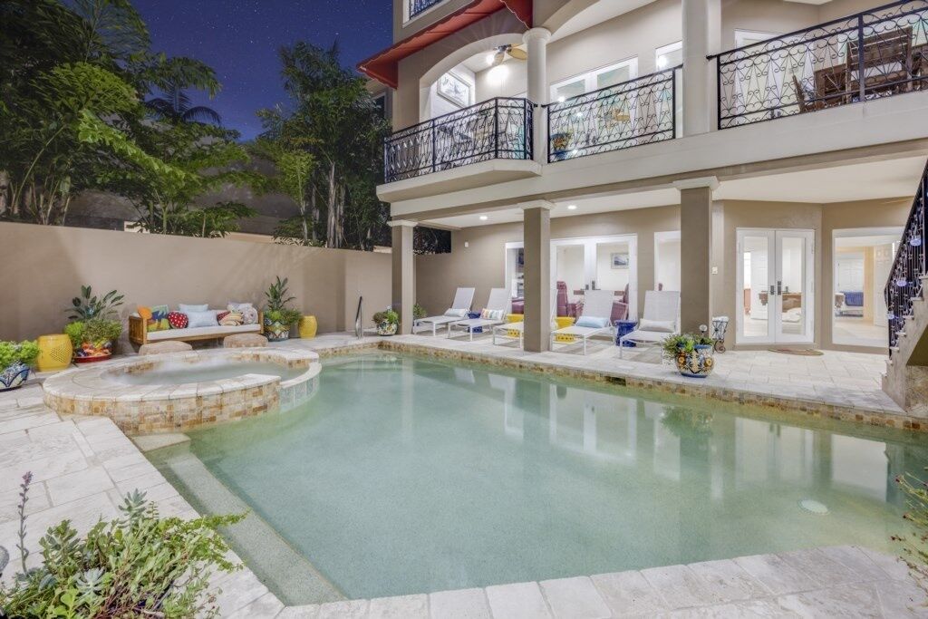 A two-story building with a swimming pool, outdoor seating, and a balcony with a railing.
