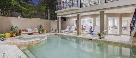 A two-story building with a swimming pool, outdoor seating, and a balcony with a railing.