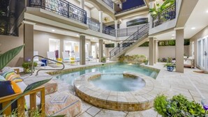 Ein Poolbereich im Innenbereich mit mehreren Ebenen, einer Whirlwanne, Liegestühlen und einer Treppe.