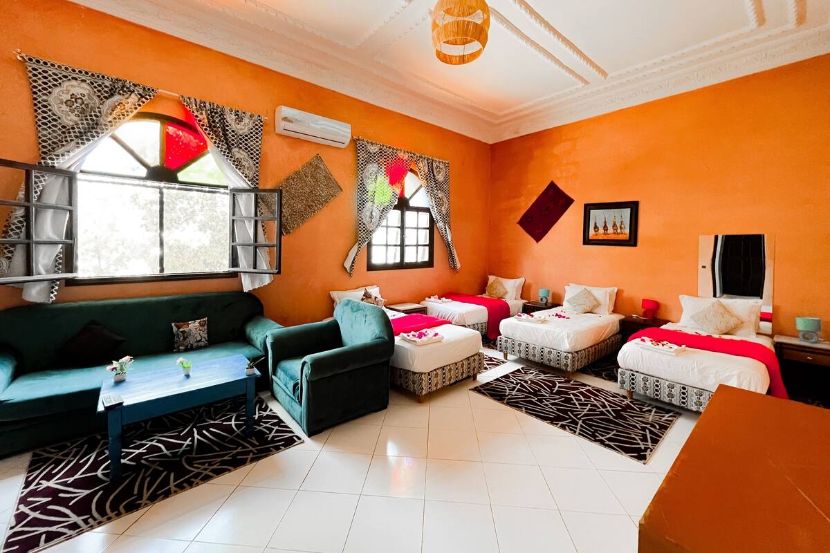 A hotel room with two beds, a sofa, a coffee table, and a dining table.
