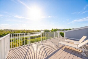Une terrasse en bois avec une balustrade blanche, un mur blanc et un fauteuil de jardin blanc.