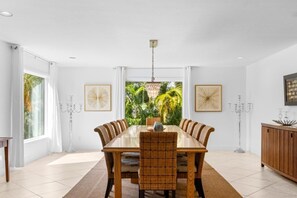 Ein Esszimmer mit einem großen rechteckigen Tisch, sechs Stühlen und einer Chandelier.