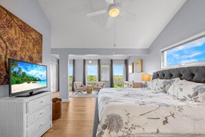 Ein Schlafzimmer mit Bett, Fernseher, Deckenventilator und Blick ins Freie.