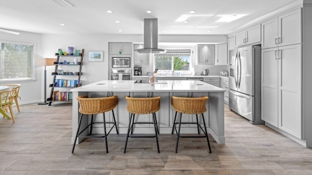 A modern kitchen with a large island, stainless steel appliances, and a view to the outdoors. - Osprey House 4 Bedroom Home by RedAwning (Sanibel)