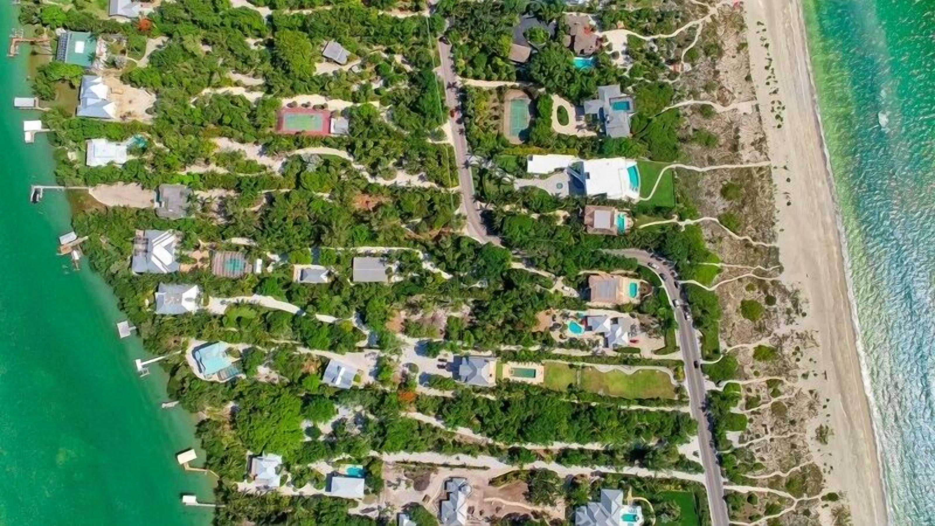 An aerial view of a coastal resort with multiple villas, a beach, and a marina.