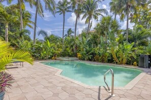 Relax by the serene pool surrounded by lush tropical vegetation and a tiled deck.