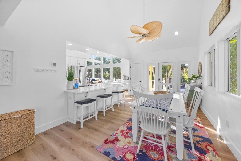 A bright kitchen with white cabinets, a central island, and a ceiling fan.