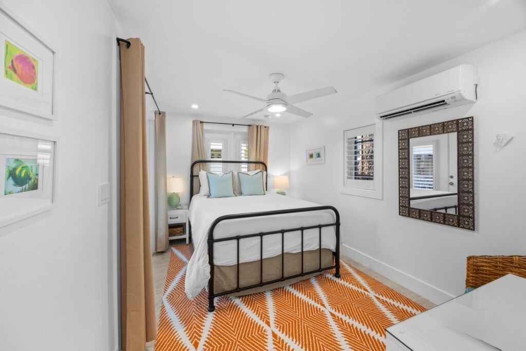 A bedroom with a bed, bedside table, and a mirror on the wall.