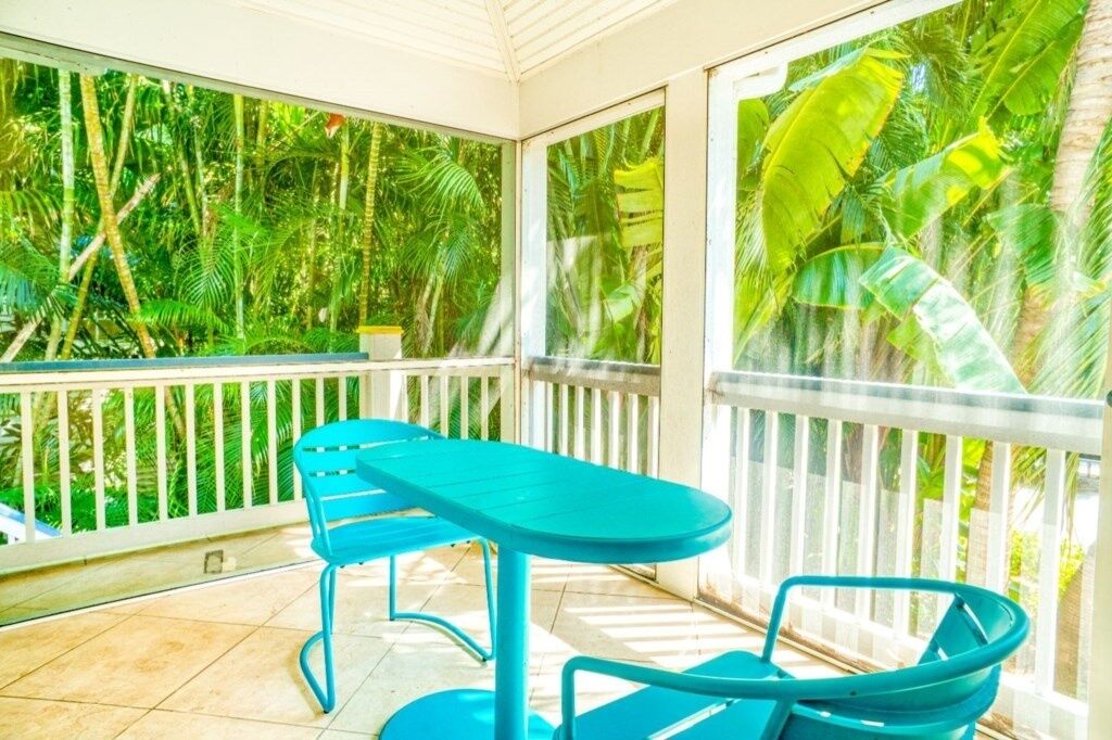 A balcony with a table and chairs, surrounded by lush tropical vegetation.