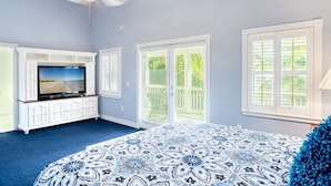 A bedroom with a large bed, a TV on a white cabinet, and a ceiling fan. - Lollipop 3 Bedroom Home by RedAwning (Captiva)