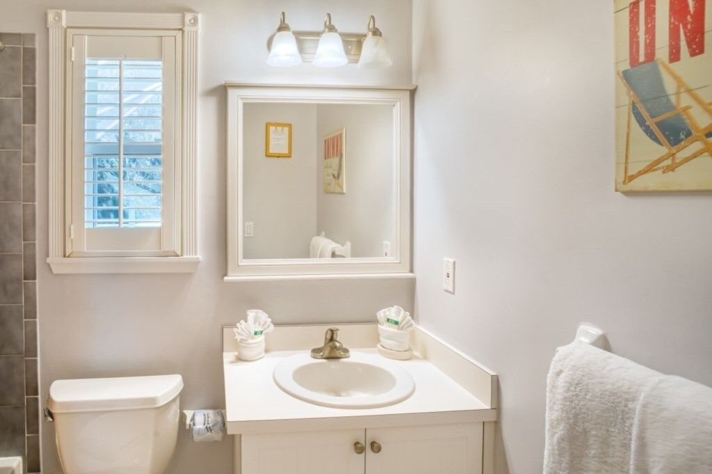 Une salle de bain équipée de toilettes, d’un lavabo, d’un miroir et d’un porte-serviettes.