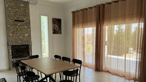 A dining area with a stone fireplace, a large table, and black chairs. - Cheerful 2-bedroom Villa With Pool (Nasrallah)