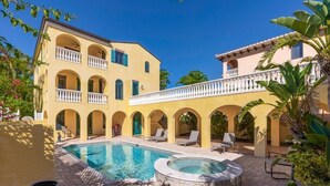 A two-story building with a pool, outdoor seating, and a covered patio area.