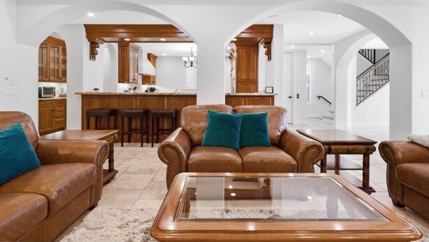 A spacious living room with leather sofas, a glass coffee table, and wooden flooring.