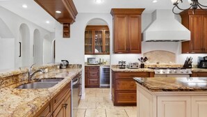 A kitchen with granite countertops, wooden cabinets, and a central island.