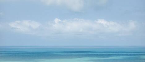 A view of a beach with clear water and a cloudy sky.