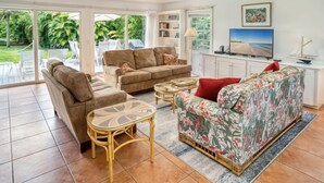 A spacious living room with a sofa, armchairs, and a television.