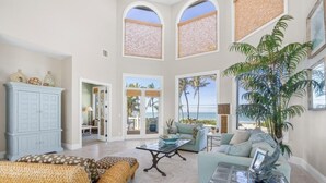 A spacious living room with a high ceiling, large windows, and a view of the outdoors. - Captiva Grace 5 Bedroom Home by RedAwning (Captiva)