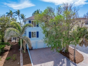 A two-story house with a paved driveway and palm trees. - Anchored Here 3 Bedroom Home by RedAwning (Captiva)