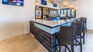 A bar area with a counter, bar stools, and hanging light fixtures. - Lovely 5br Townhouse At Windsor At Westside 5 Bedroom Townhouse by RedAwning (Kissimmee)