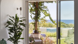 A bedroom with a large bed, a desk with a chair, a potted plant, and a view of the outdoors. - Two king-size bedrooms villa with pool and sea view (FORIO)