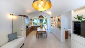 A modern kitchen with a dining area, white cabinetry, and a large pendant light. - Two king-size bedrooms villa with pool and sea view (FORIO)